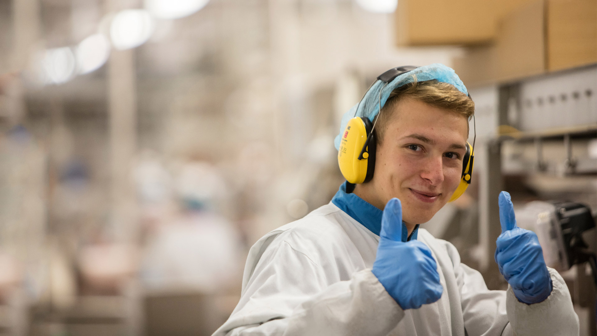 Safe & well A man with earphones and blue gloves gives a thumbs up in a laboratory